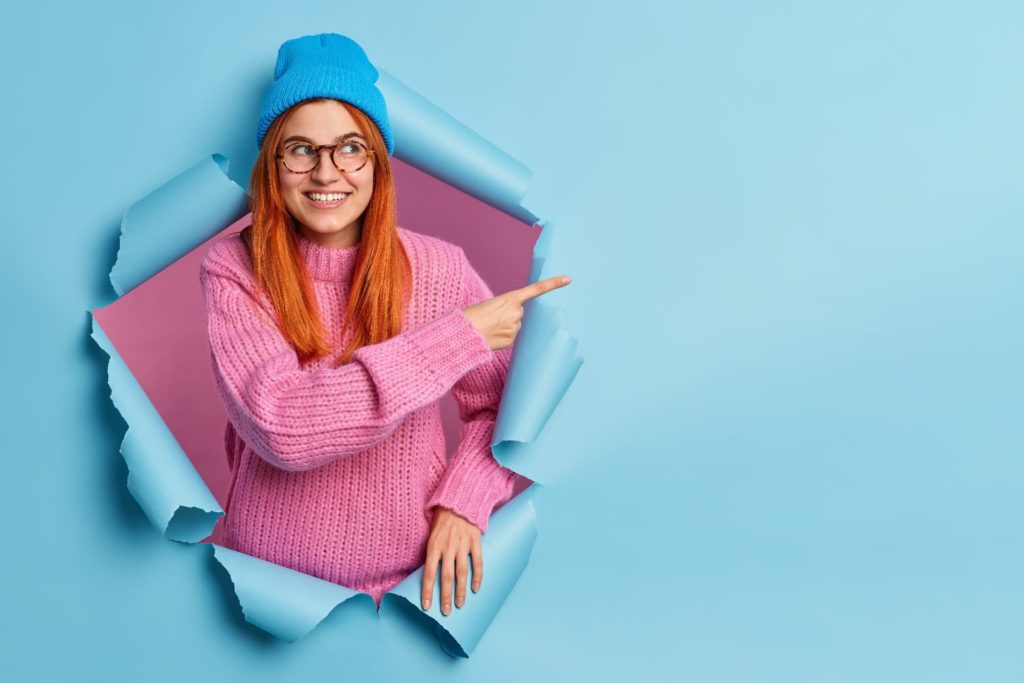 pretty smiling redhead woman blue hat knitted sweater points copy space 1